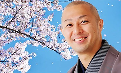 San'yutei Ponta in front of a blooming cherry tree