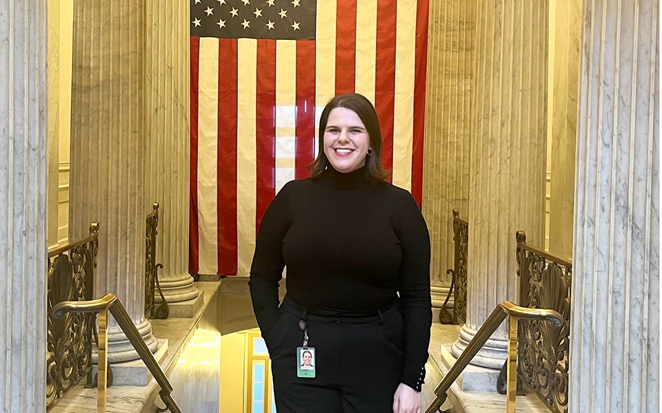 Alexa Cooley in a government building with a flag and marble pillars in the background.