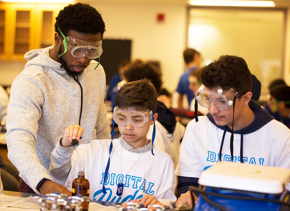 Two middle school boys are supervised doing a lab experiment at a Digital Dudes event.