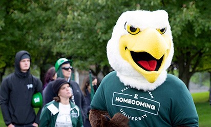 Swoop wearing a homecoming t-shirt with students in the background.