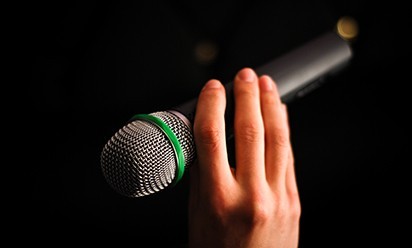 a hand holding microphone against a dark background