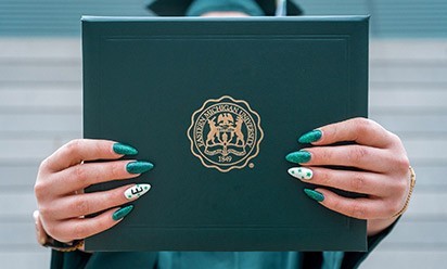 Fancy, green-and-white manicured fingernails hold an EMU diploma