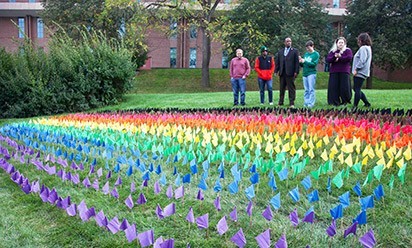 People stand behind the rainbow flags on Pray-Harrold lawn.