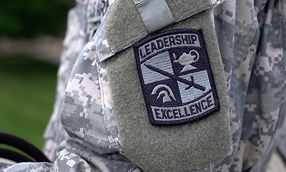An ROTC arm patch reads, "Leadership, Excellence" on a digital cammo sleeve.