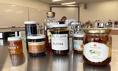 A variety of honey containers on the table at the lab. 