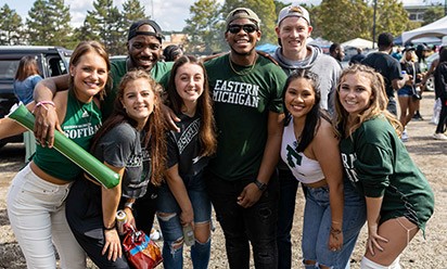 A group of diverse students smile for the camera at a Homecoming event.