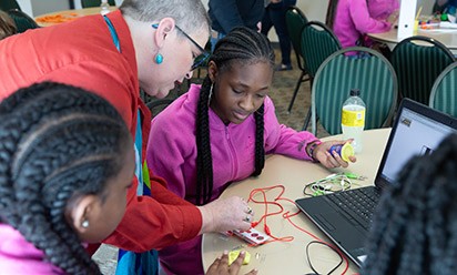 A Digital Divas presenter helps middle schoolers with a hands-on activity.