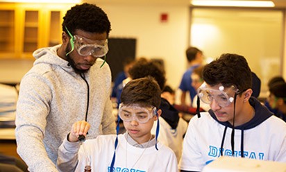 Two middle school boys are supervised doing a lab experiment at a Digital Dudes event.
