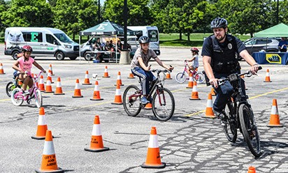 An EMU policeman and kids on bikes at a safety course.