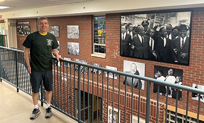 Aaron Liepman stands by the "Walk to Freedom" art wall at the Honors College.