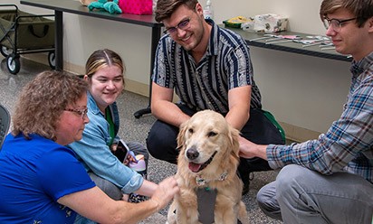 Tinker, facility dog at EMU, gets petted by students and staff.