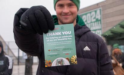 A volunteer hold up a "Thankful for You" flyer at the Thanksgiving food drive-through giveaway.