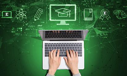 overhead view of hands on a laptop with graphic icon of a grad cap and other college symbols