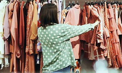 A person looks through clothes on a rack.