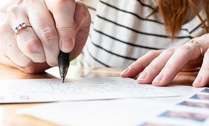 A young person's hands writing on a postcrd