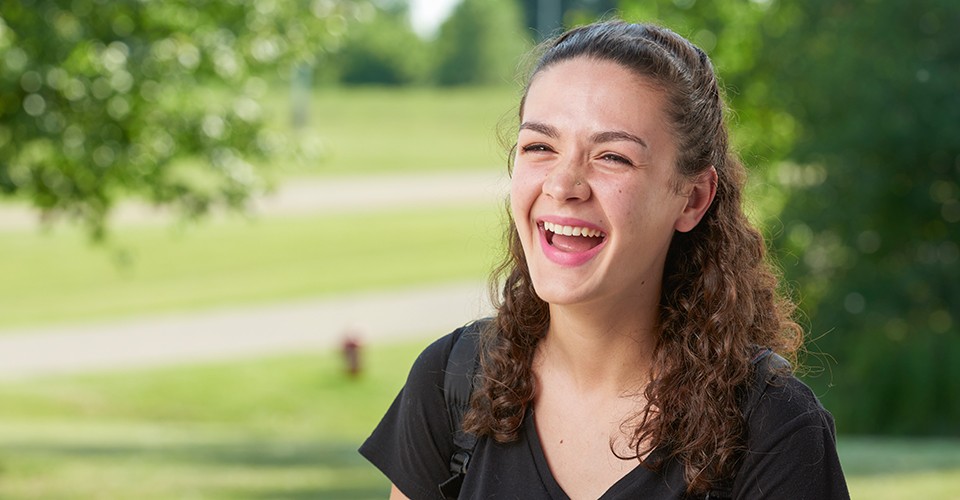 Sydney Lawson, an OCC student that is transferring to EMU, laughs out loud outside on a sunny day.