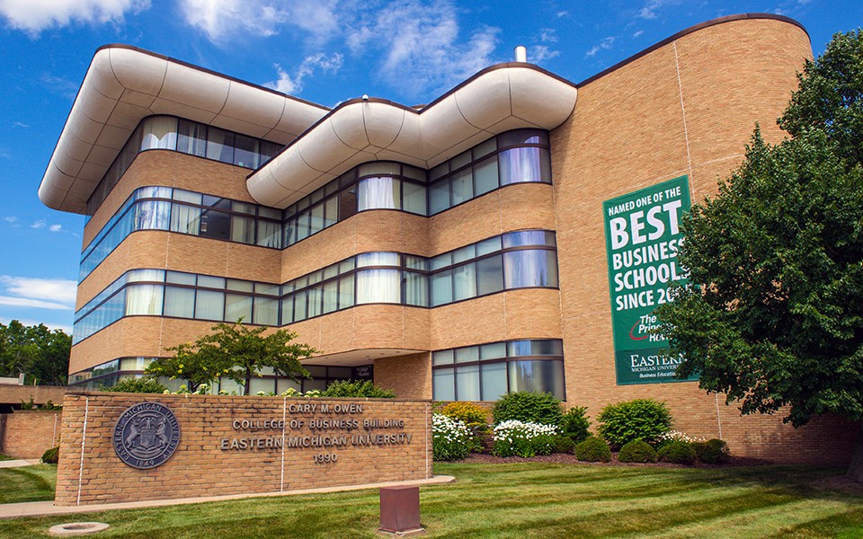 The exterior of EMU's College of Business Gary M. Owen building with "Best Business School" banner on the bricks.
