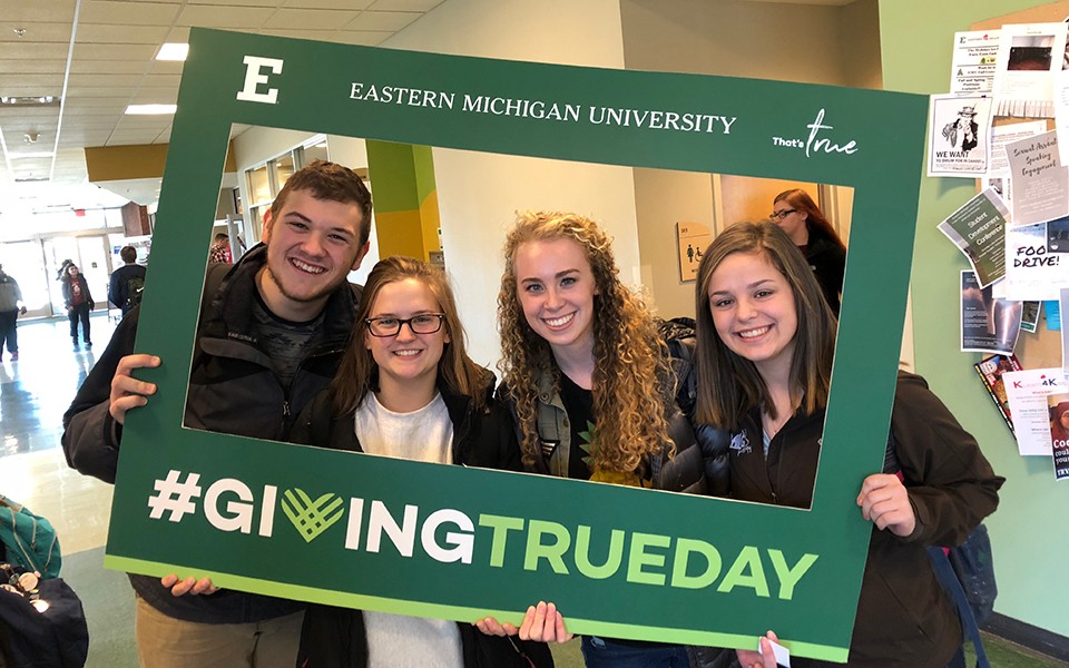 Students pose for picture in GivingTRUEday photo frame