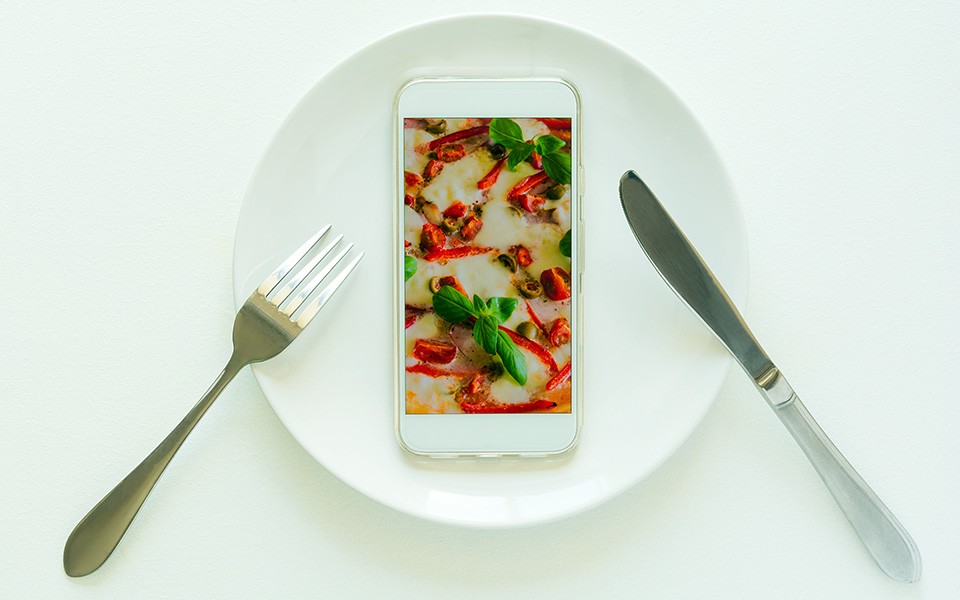 Photo illustration of table setting and phone with food showing on screen