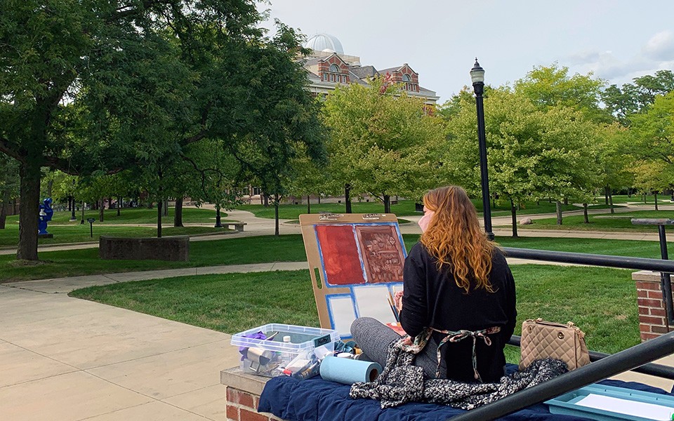 Art student painting outside on campus