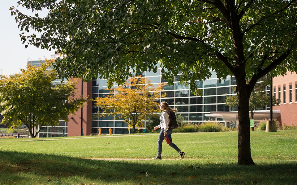 A student walking on campus by the Student Center in the fall