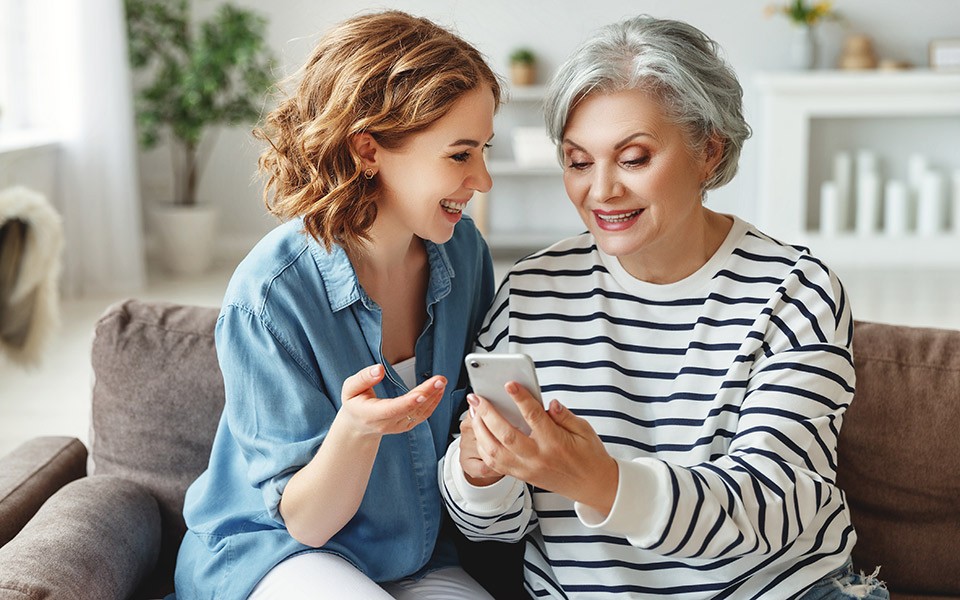 A young woman helping an older woman use a smartphone
