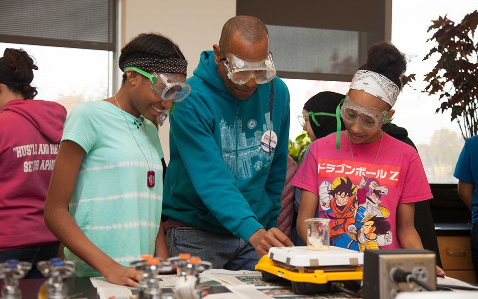 A teacher works with young girls on a chemistry  project at Digital Divas 2019.