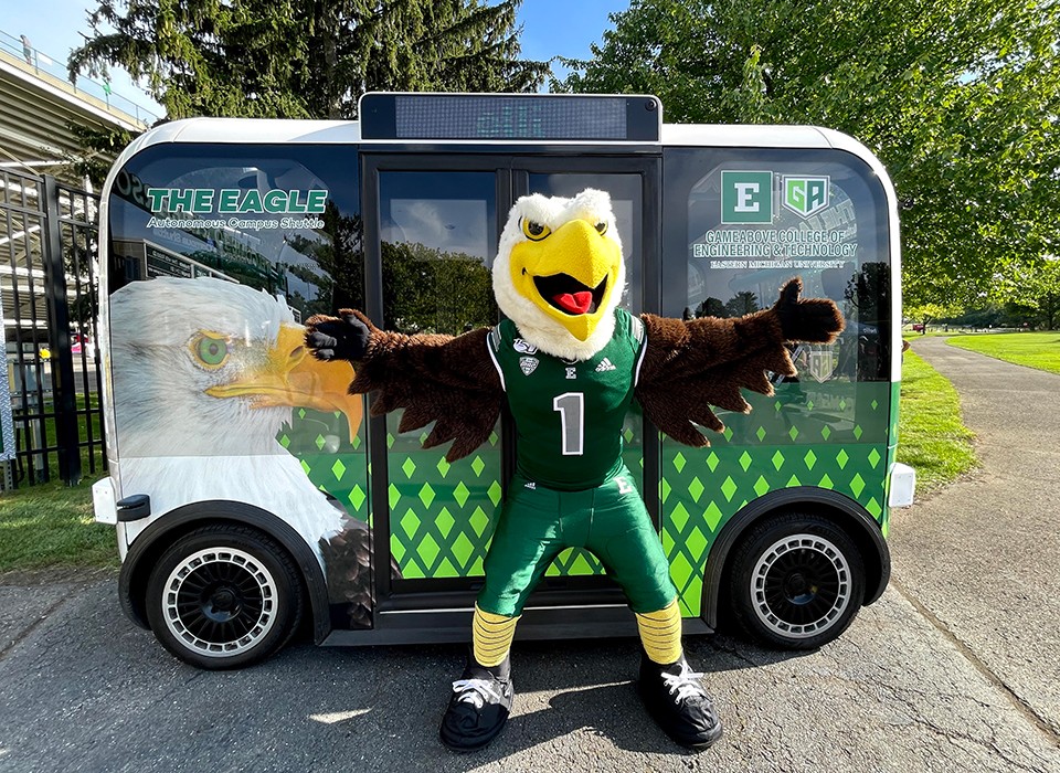 Swoop poses in front of the autonomous shuttle, the Olli