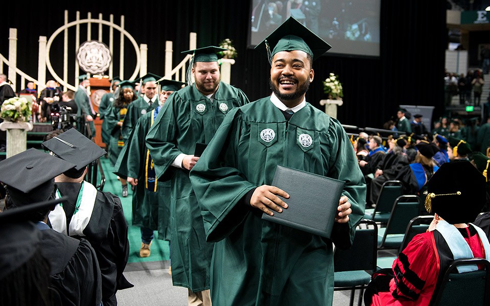 New graduates walk down the aisle at the Convocation Center after having received their diplomas