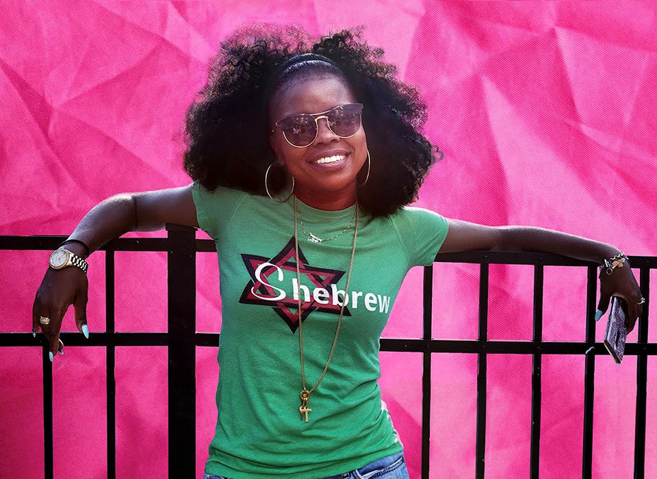 Tamar Manasseh leans on a fence wearing a Star of David and "Shebrew" printed on her t-shirt for the "They Ain't Ready for Me" documentary film.