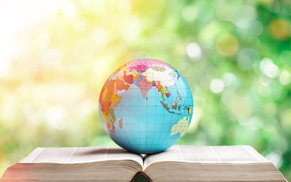 A globe rests on an open book outdoors on a sunny day