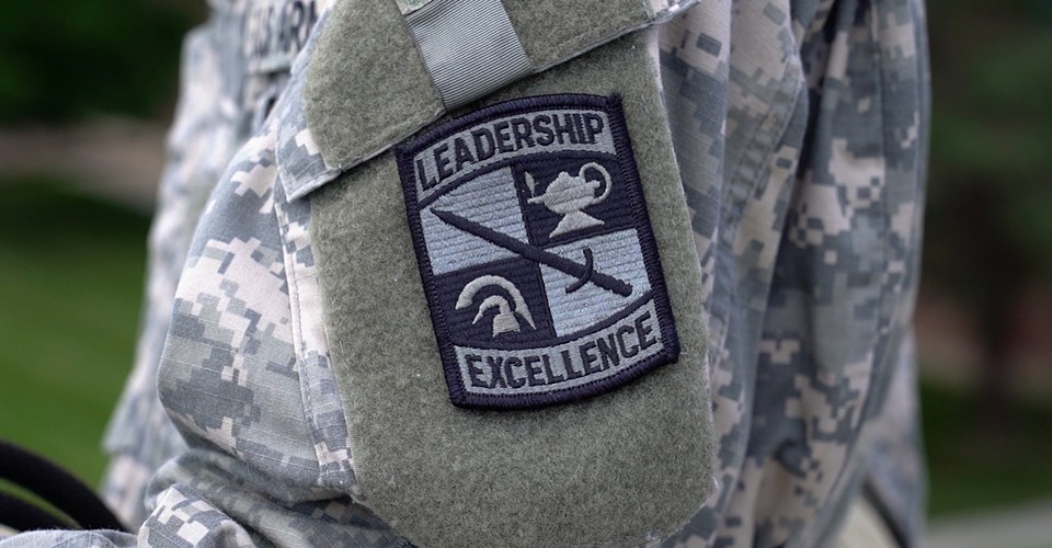 A camouflage uniform sleeve with patch embroidered with military symbols and the words "Leadership," and "Excellence."