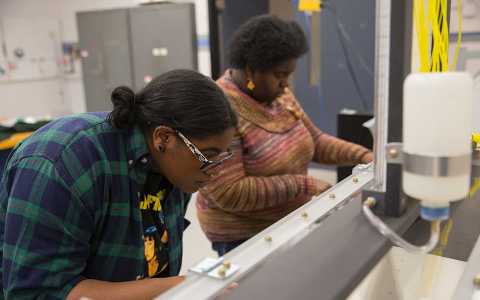 Two African American women work on a project in the engineering/technology classroom.