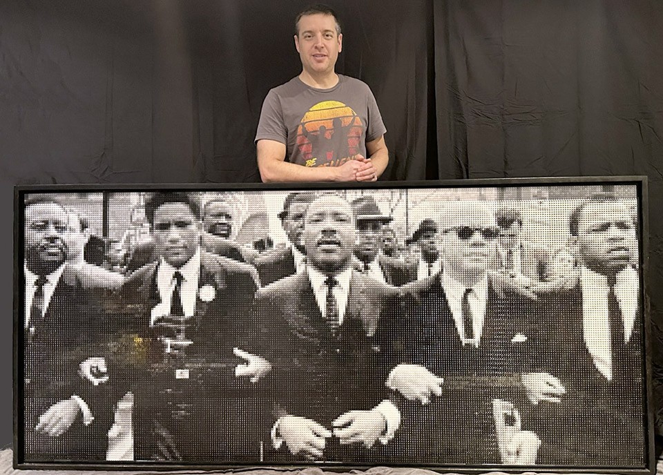 Aaron Liepman standing behind the large LEGO installation of the 1965 march from Selma to Montgomery with MLK in the center.