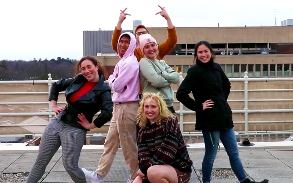 A group of students in the creative coding video pose at the finale on the roof of a campus building