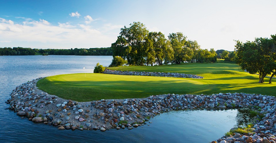 One of the holes at Eagle Crest golf club, surrounded by water and rocks, is lit by the sun.