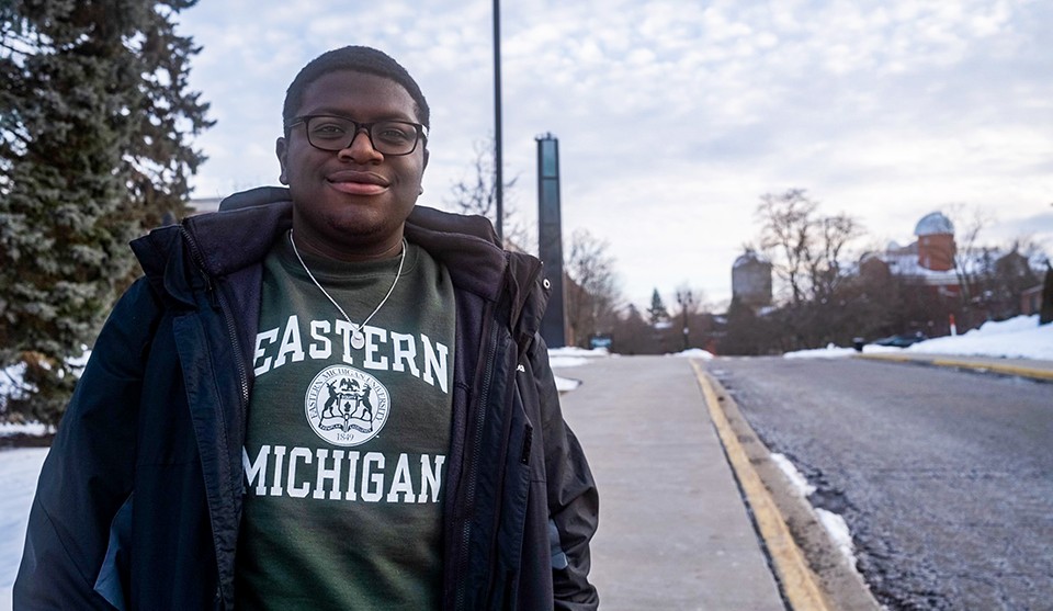 Cedrick Charles stands outside on campus with the Sherzer dome in the background.