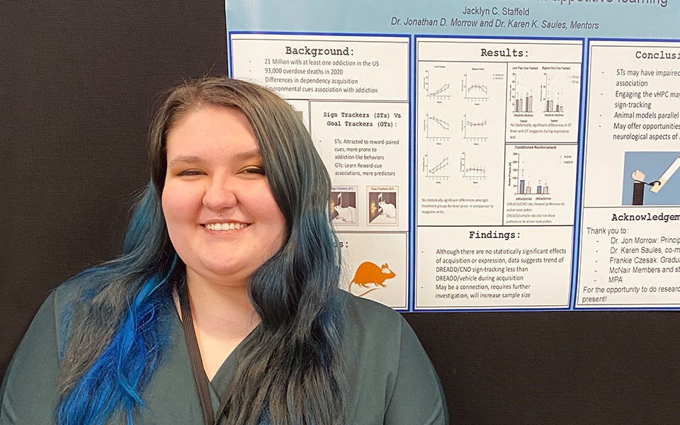 Jacklyn Staffeld stands in front of her research presentation poster.