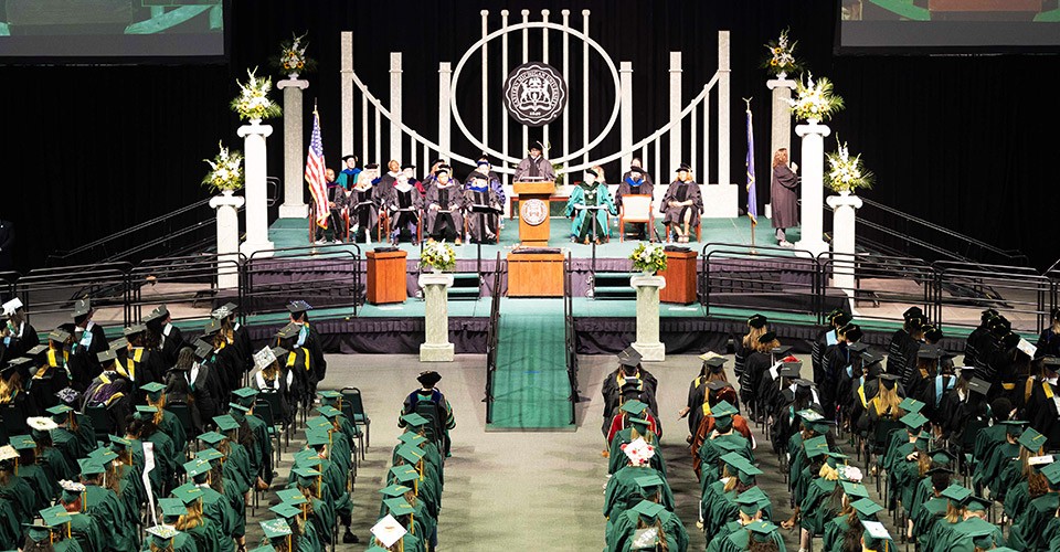 A view from above of the platform and podium, and graduates in rows of chairs at a commencement ceremony
