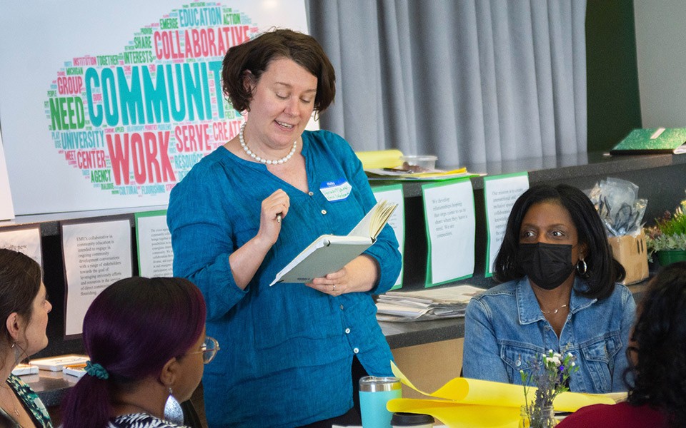 A woman, standing, participates in a group activity at EMU's COE-hosted workshop.