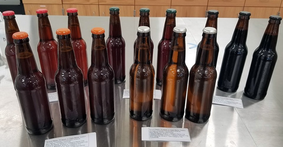 Bottles of different types of beer are lined up on a table.