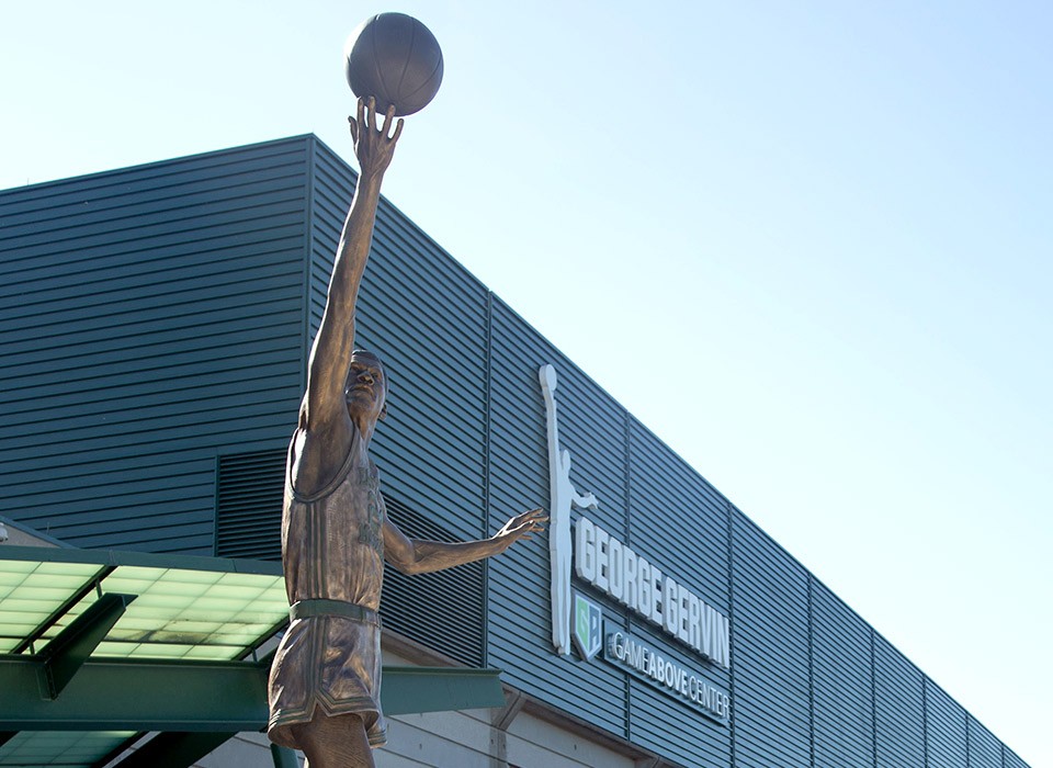 The George Gervin statue in front of the GameAbove Center on a sunny day.