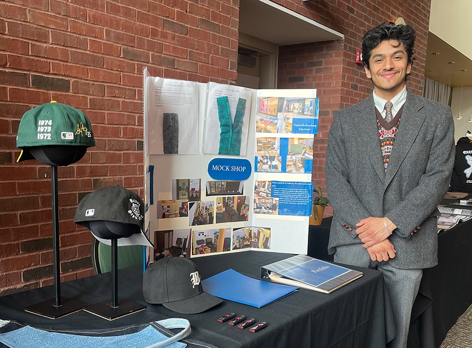 A student stands next to his fashion marketing innovation project