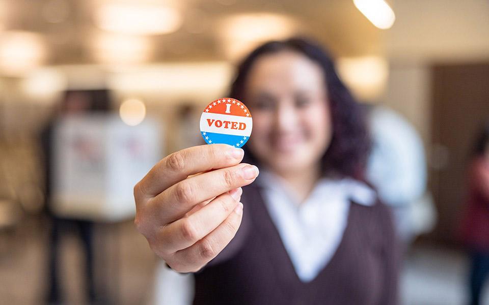 A woman holds an "I Voted" button in her hand