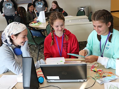 Girls around a computer at the Digital Divas event.