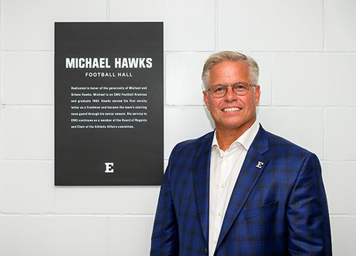 Regent Michael Hawks stands by the plaque of the football hall named in his honor.