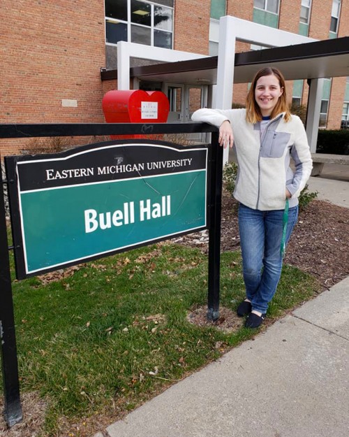 Kerry Ryan stands by an EMU residence hall sign.