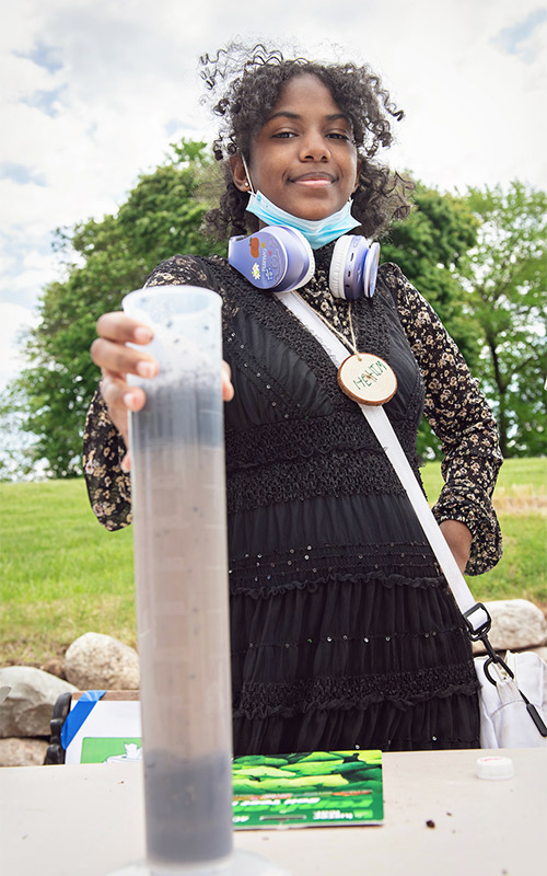 Student holds water testing equipment on Belle Isle